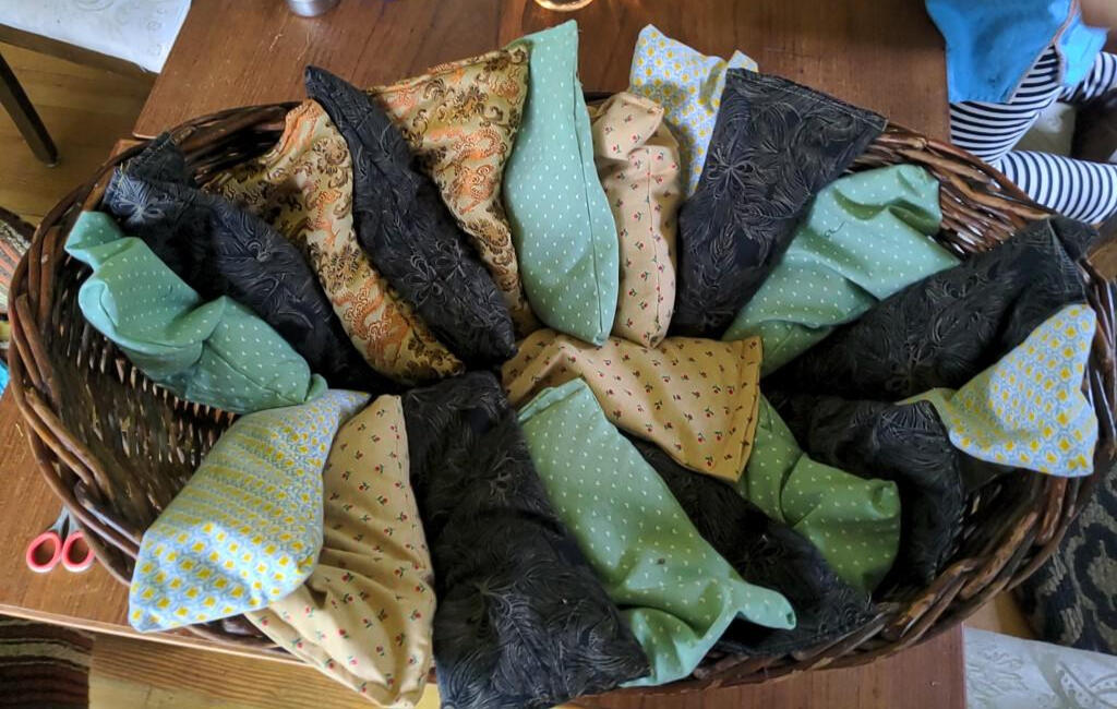 A basket filled with long rectangular eye pillows made with fabric of different patterns